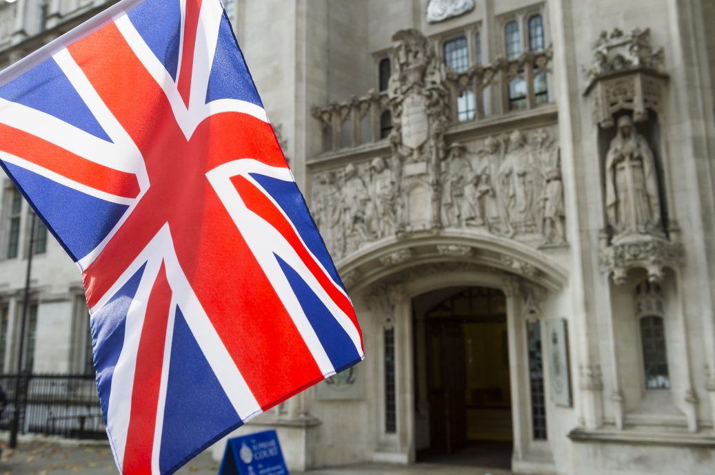 British Union Jack flag flying in front of The Supreme Court of the United Kingdom in the public Middlesex Guildhall building in Parliament Square in London