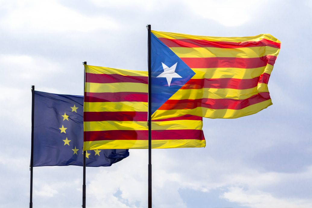 Flags of European Union and Catalonia with the Catalan secessionist flag waving together on a cloudy sky