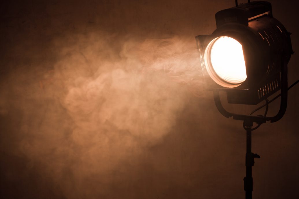 theater spot light with smoke against grunge wall