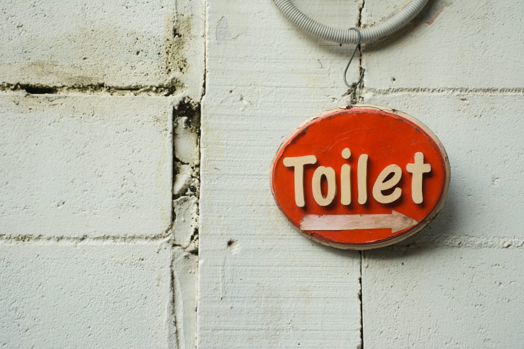 Retro Red Toilet sign on white brick wall