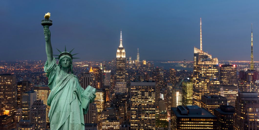 United States of America concept with statue of liberty in front of the New York cityscape at night