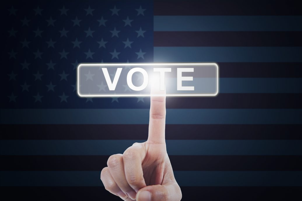 Hand touching vote button with american flag