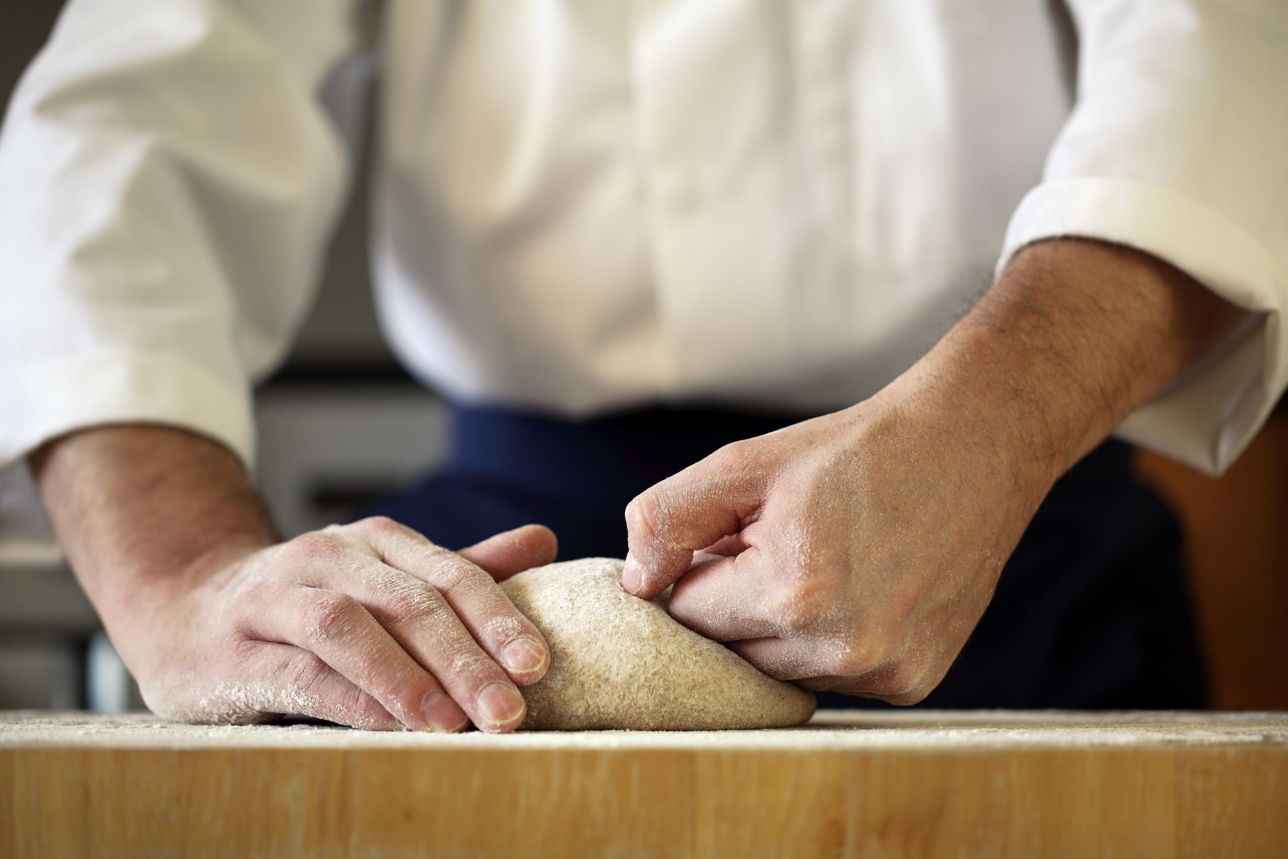 Making bread yeast dough, chef kneading in a bakery kitchen