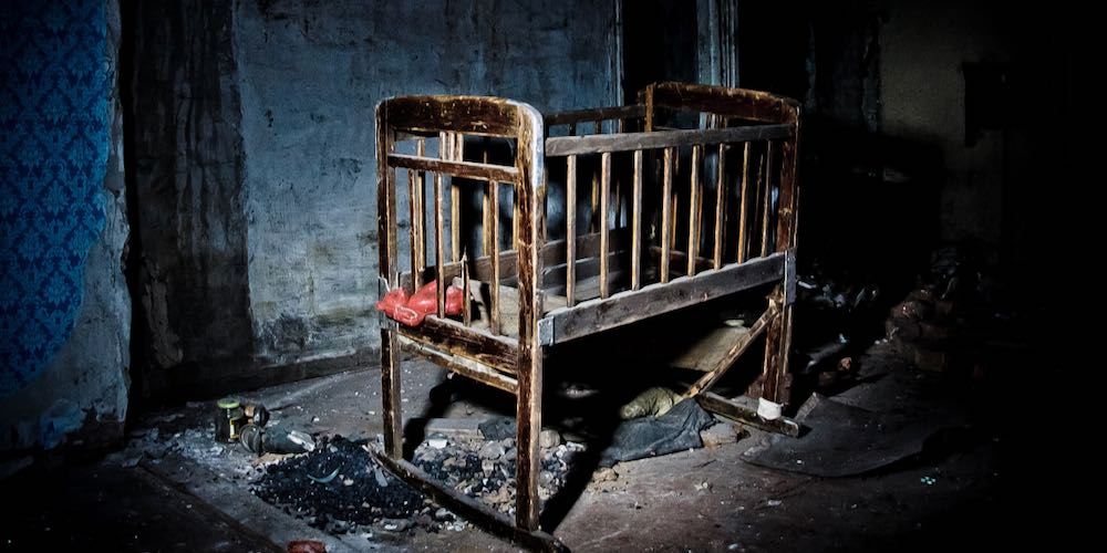 Old creepy eerie wooden baby crib in abandoned house. Horror concept.